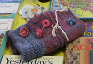 A twiddle muff occupies fidgety fingers.  Hand knitted by volunteers and with buttons, ribbons and other items stitched into the muff