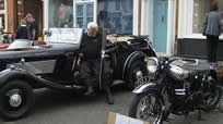 Gentleman and his vintage car parked next to a vintage motorcycle