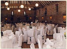 The Cross Barn prepared for a wedding breakfast with the chairs in white covers